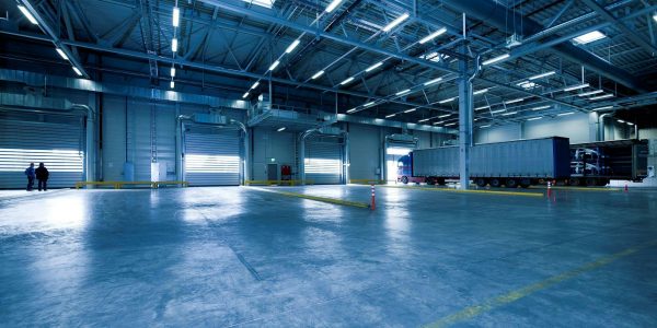 Wide view of an empty modern warehouse with industrial lighting and trucks.