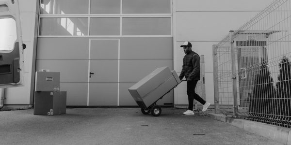 Black and white photo of a delivery worker moving packages outside a warehouse.