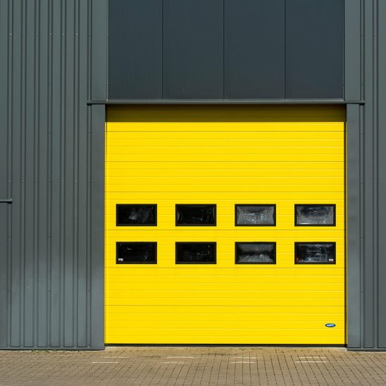 A sleek industrial structure featuring a vibrant yellow garage door for architectural interest.